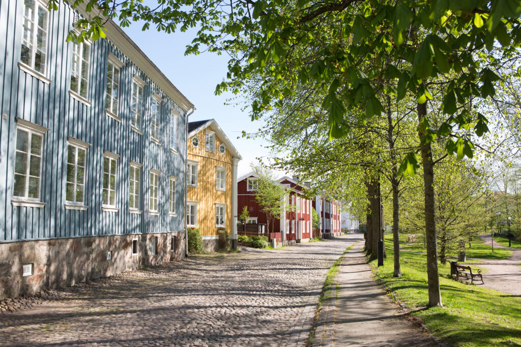 Färgglada gamla trähus längs grönskande gata